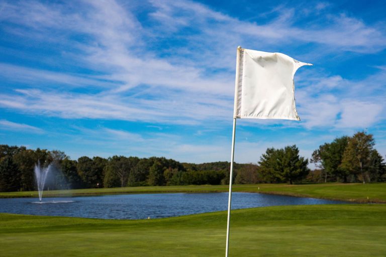 A photo of a hole flag with a lake in the back